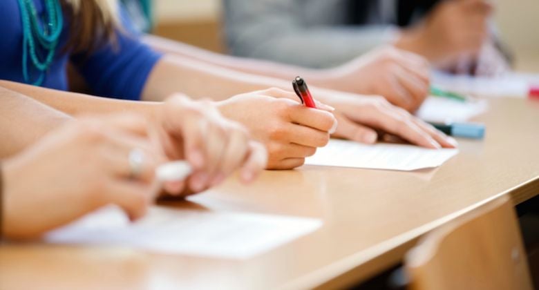 Close up of hands holding pens and marking on papers